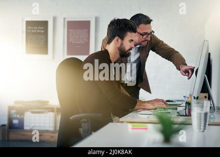 Working together brings out the best in us. Shot of two designers discussing something on a computer screen. Stock Photo