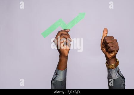Black person holding an upward graph symbol showing progress Stock Photo