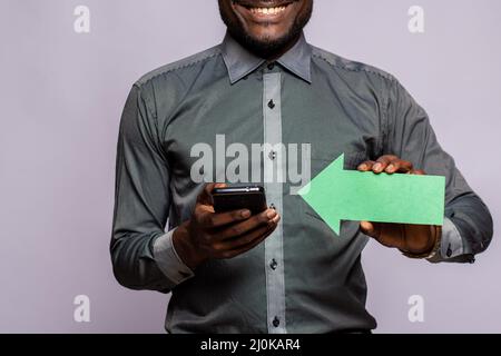 Happy black man holding phone and arrow pointing to it Stock Photo