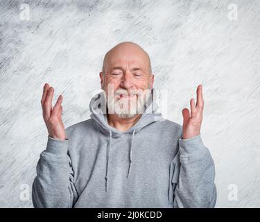 casual, portrait of happy and smiling gesticulating senior man wearing hooded sweatshirt Stock Photo