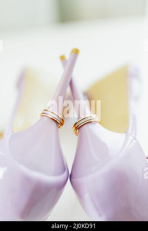 Wedding gold rings on the heels of purple bride's shoes. Stock Photo