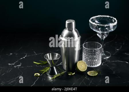 Cocktail shaker and cocktail glasses, and ingredients on dark marble background Stock Photo