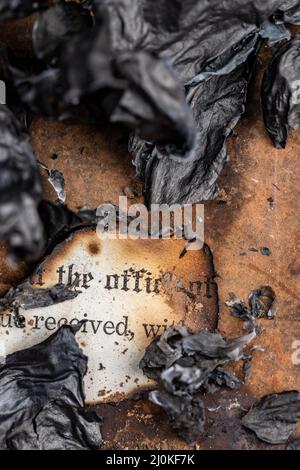 Old burned paperwork surrounded by burnt paper ashes Stock Photo