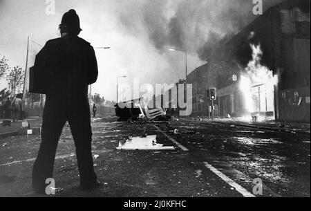 Toxteth Riot 5th July 1981A police officer in riot gear stands amongst the broken glass and burning shops in Park Road  The riots was sparked following the interception by police of motorcyclists Leroy Cooper in Selbourne Street. A crowd gathered, name-calling grew into jostling and within minutes there was a full-scale fracas that saw three police officers hurt and a young local man, arrested on assault charges. It did not stop there. Police mounted extra patrols in the area and early the following evening, July 4, they came under attack from a crowd armed with bricks and petrol bombs. The fu Stock Photo