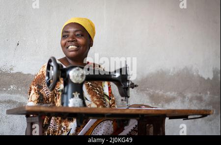 African female tailor working on sewing machine on street Stock Photo