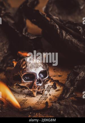 Old Skull Ring surrounded by burnt paper ashes Stock Photo