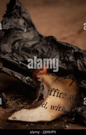 Old burned paperwork surrounded by burnt paper ashes Stock Photo