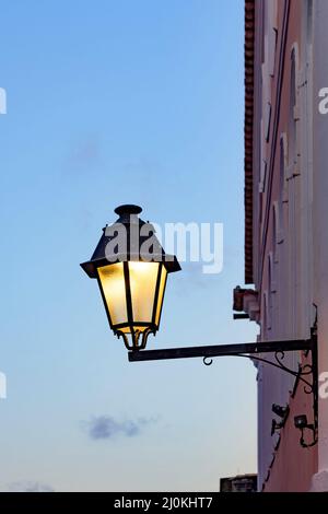 Old metal lanterns on the wall of a colonial house with the sky in the background during nightfall Stock Photo