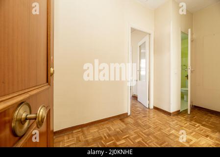Entrance door and distributor hall of a residential house with entrance to a furnished living room, toilet and oak parquet floors Stock Photo