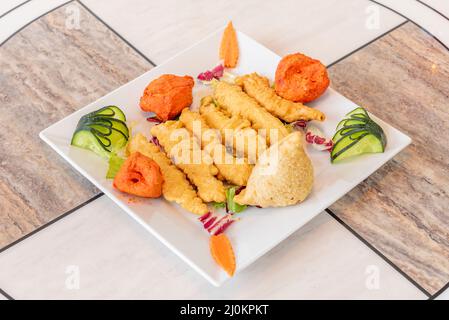 Indian appetizer platter with onion batter, chicken tikka masala pieces and meat-filled samosas Stock Photo