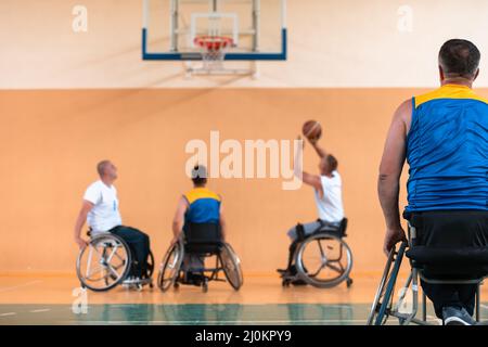Disabled War veterans mixed race and age basketball teams in wheelchairs playing a training match in a sports gym hall. Handicap Stock Photo