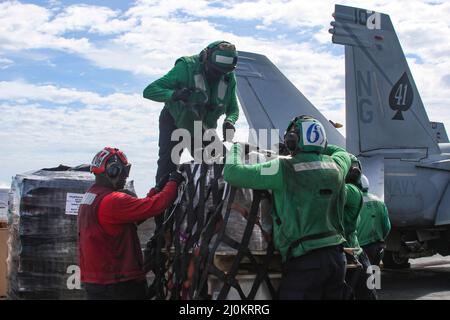 PHILIPPINE SEA (March 18, 2022) Sailors remove cargo nets on the flight deck of the Nimitz-class aircraft carrier USS Abraham Lincoln (CVN 72) during a vertical replenishment-at-sea with the Military Sealift Command dry cargo and ammunition ship USNS Matthew Perry (T-AKE 9). Abraham Lincoln Strike Group is on a scheduled deployment in the U.S. 7th Fleet area of operations to enhance interoperability through alliances and partnerships while serving as a ready-response force in support of a free and open Indo-Pacific region. (U.S. Navy photo by Mass Communication Specialist Seaman Apprentice Jul Stock Photo