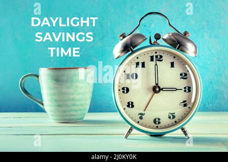 Daylight Saving Time concept. A retro alarm clock with a cup of coffee Stock Photo