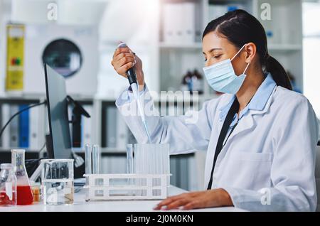 Experimenting makes me happy. Shot of a young female researcher working in a laboratory. Stock Photo