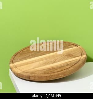 Round wooden kitchen pizza board on a green background, utensils levitate, copy space Stock Photo