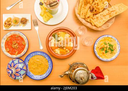 Colorful Moroccan food plates with couscous, lamb tagine, baklava, hummus and smoothies Stock Photo