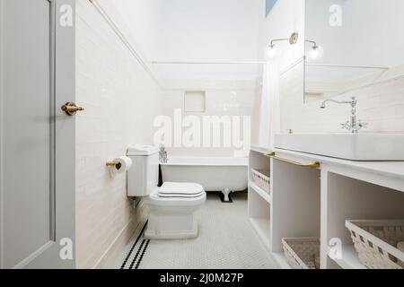 Bathroom decorated with a white porcelain sink on a white marble countertop with built-in mirrors and vintage chrome faucets and a claw-foot bathtub i Stock Photo