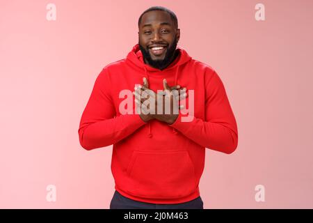 Pleased touched african american smiling young bearded man hold hands heart grinning thanking heartwarming lovely congratulation Stock Photo