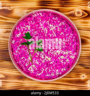 Traditional Russian holiday salad Herring under a fur coat (shuba) with sprigs of fresh green parsley on a wooden background top Stock Photo