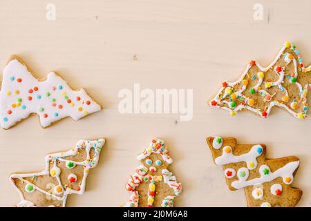 The arrows point to the center. Homemade gingerbread in the shape of Christmas trees, on white painted wood texture. Stock Photo