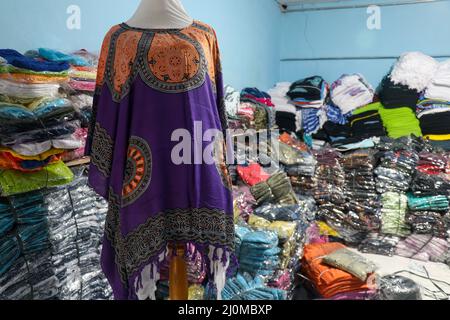 Poncho on a mannequin. Packages of colorful fabrics and variations of batik sarongs in a store in a traditional Asian market Stock Photo