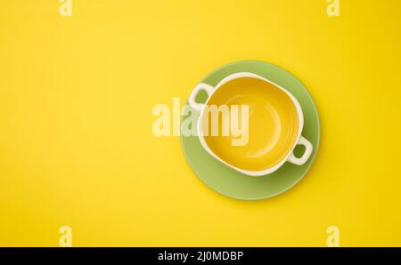 Empty yellow soup plate on a yellow bacground, top view Stock Photo