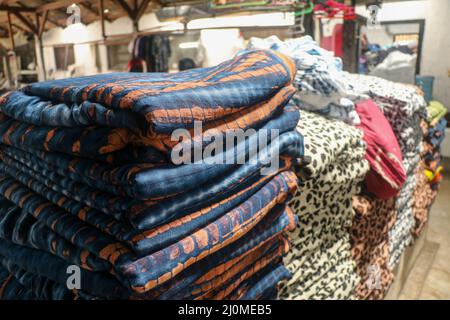 A stack of multi-colored towels on a light background, side view. Close up of a stack of colorful rugs for sale in Indonesia at a market Stock Photo