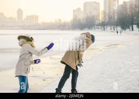 Young Caucasian people in love heterosexual couple have a date in winter near a frozen lake. Active holiday holiday Valentine's Stock Photo