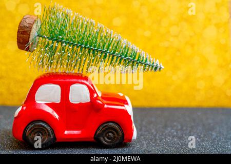 Red toy car carries a Christmas tree for the holiday. Stock Photo