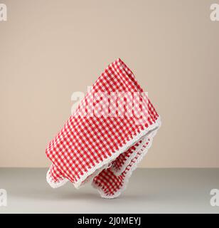 Red and white checkered kitchen towel levitates on beige gray background Stock Photo