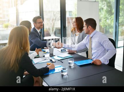 Glad to have you on board. Cropped shot of two businessmen shaking hands while sitting in a meeting. Stock Photo