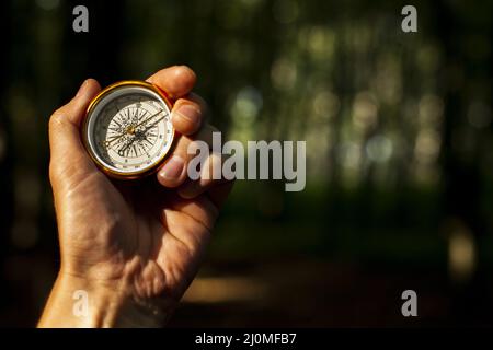Hand holds compass with blurred background