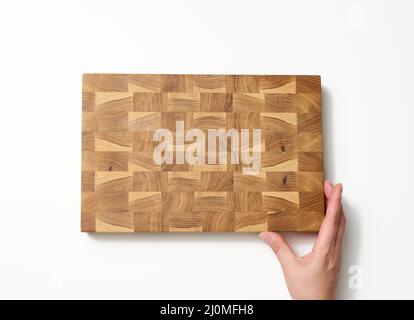 Female hands hold empty rectangular brown wooden chopping board on white background Stock Photo