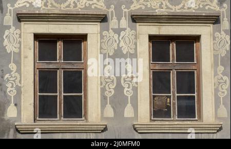 Vintage style old wooden windows with ornaments on the wall. Exterior of a building. European classic style window panels on an Stock Photo