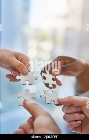 Joining together as a team. Shot of hands putting puzzle pieces together. Stock Photo
