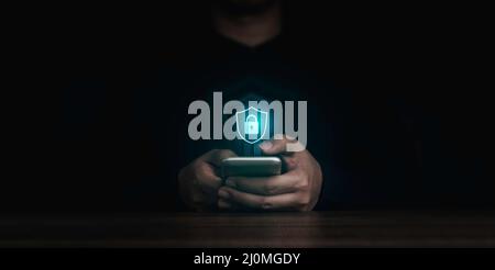 Shield lock button and personal information icons appeared while man's finger touching on smart mobile phone on dark background. Cyber security, data Stock Photo