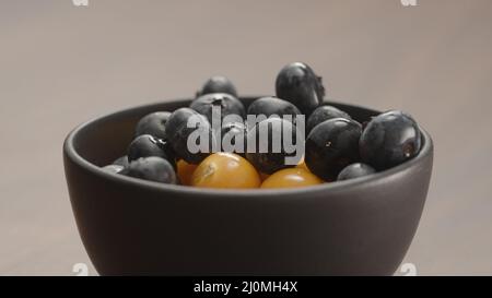 blueberries in black bowl with physalis closeup, wide photo Stock Photo