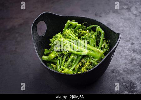 Fresh rapini broccoli rabe with sesame as top view on a black bowl with copy space Stock Photo