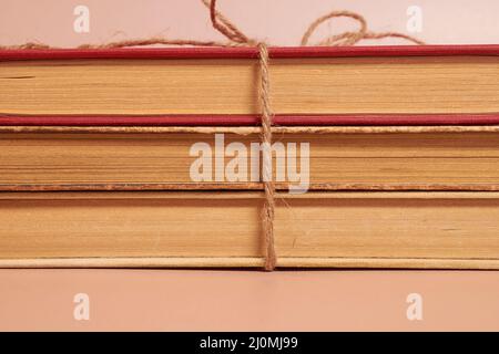 A stack of old battered books tied with a jute rope on a colored background Stock Photo