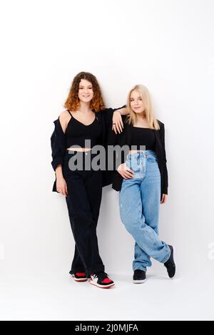 Two teen girls lean on each other over white studio background Stock Photo