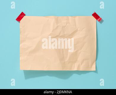 Blank rectangular crumpled beige sheet of paper glued on a light blue background. Place for an inscription, announcement Stock Photo
