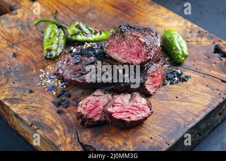 Traditional barbecue wagyu onglet steak with green chili and spices served as close-up on a rustic wooden board Stock Photo