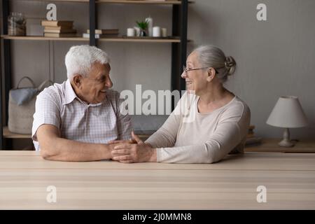 Senior grandparents sit at table holding hands feeling love Stock Photo