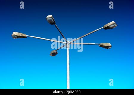 Old weathered street lamp with five arms to which are attached blind lamp, abstract, blue background Stock Photo