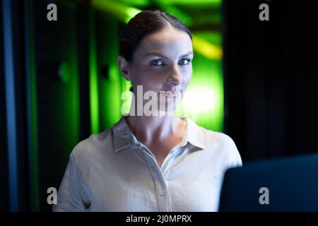 Portrait of caucasian female engineer with laptop in computer server room Stock Photo