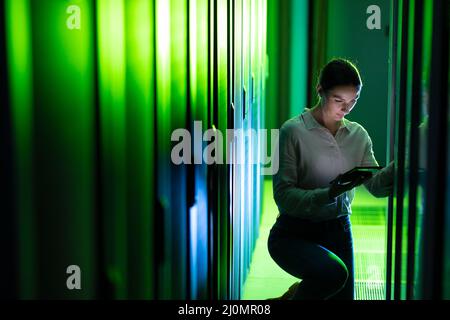 Caucasian female engineer using digital tablet while inspecting in computer server room Stock Photo
