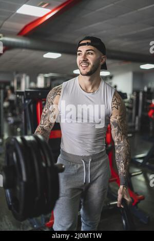 Tattooed middle aged bearded black man doing sitting at a gym - Stock Image  - Everypixel