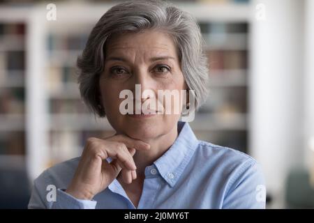 Beautiful grey-haired woman touch chin with hand staring at camera Stock Photo