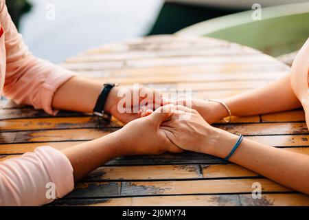 Man holds girl's hands on a wooden table. Close-up Stock Photo