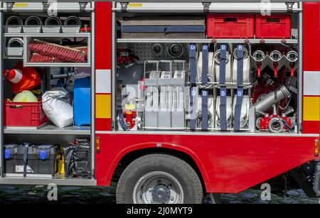 The side view of equipment inside of a fire engine. Fire truck with open hatches showing rescue equipment. Stock Photo